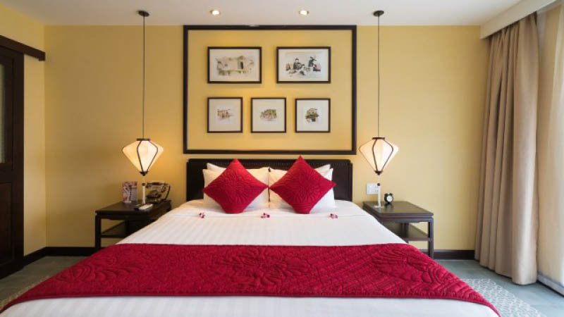 Bred dubbelsng med asiatisk inredning i dubbelrum p hotell Little hoian Central Boutique & spa i Hoi An, Vietnam.